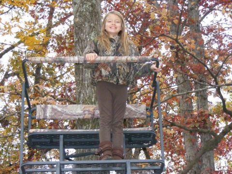 Girl in camouflage on a deer stand in a tree