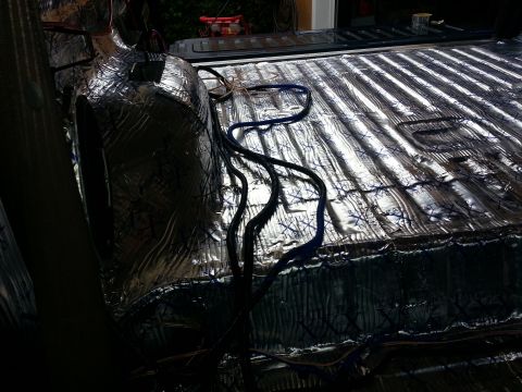 1994 Ford Bronco - Sound deadening material and wiring are visible in the bed of a truck during an installation.