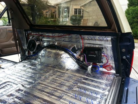 1994 Ford Bronco - The rear interior of a vehicle is shown with sound deadening material and audio equipment installed.