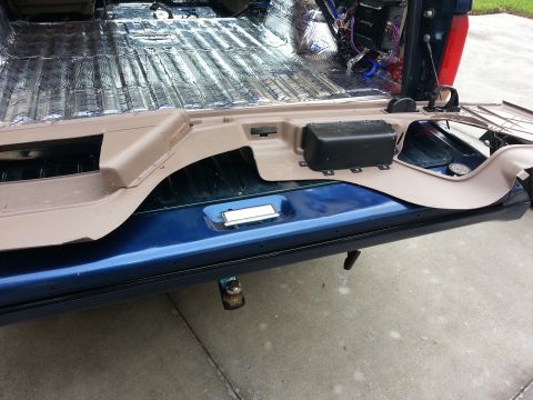 1994 Ford Bronco - The interior of a blue vehicle shows soundproofing material and a removed panel, revealing wiring and the vehicle's structure.