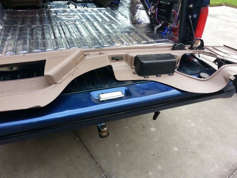 Interior of a blue vehicle with soundproofing and a removed panel, showing wiring