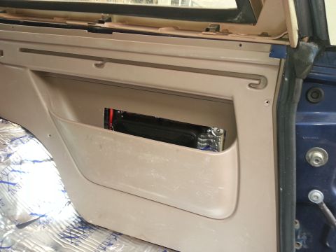 1994 Ford Bronco - Photograph of a vehicle interior quarter-panel pocket housing a battery, not a technical document.