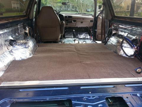 1994 Ford Bronco - Photograph of an SUV rear cargo area with carpet and foil sound-deadening, not a technical document.