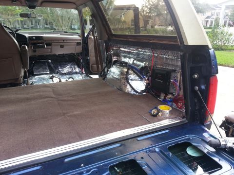 1994 Ford Bronco - Photograph of an SUV cargo area showing an amplifier, audio wiring, and foil sound-deadening, not a technical document.