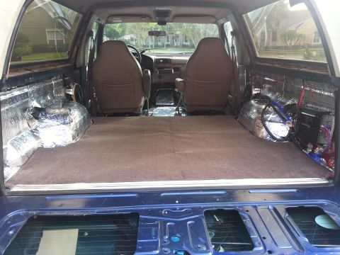 1994 Ford Bronco - Photograph of an SUV rear interior with carpet, seats, and an audio install, not a technical document.