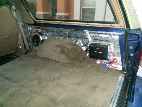 1994 Ford Bronco - Photograph of an SUV cargo corner with amplifier, subwoofer, and audio wiring, not a technical document.