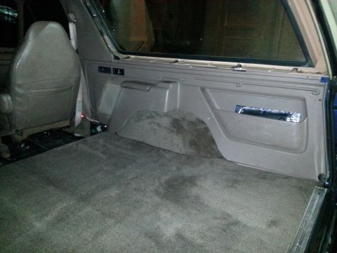 1994 Ford Bronco - Photograph of an SUV rear interior showing carpet, wheel well, and trim panel.