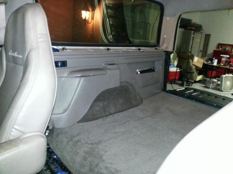 1994 Ford Bronco - Photograph of an SUV rear interior showing a leather seat, trim panel, and carpeted cargo area.