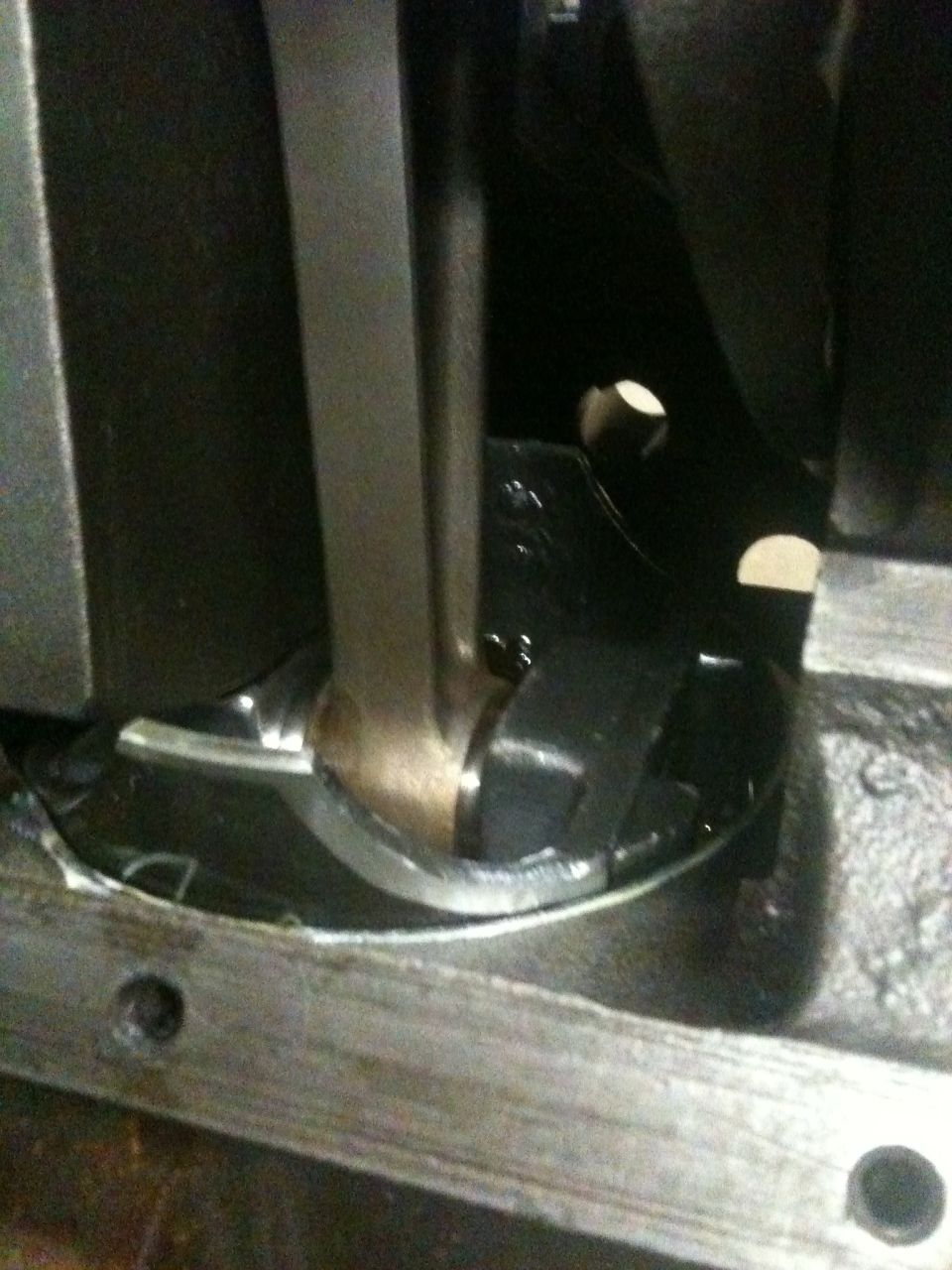 Close-up of engine or drivetrain component with connecting rod and curved metal piece.