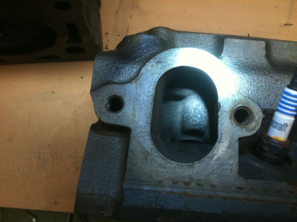 Close-up of a cast iron engine cylinder head with a spark plug.