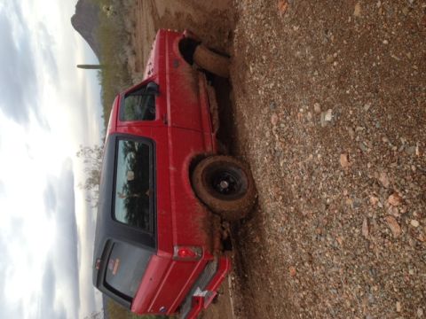 1996 Ford Bronco - This red SUV is stuck in the mud on a steep incline, with a desert landscape visible in the background.