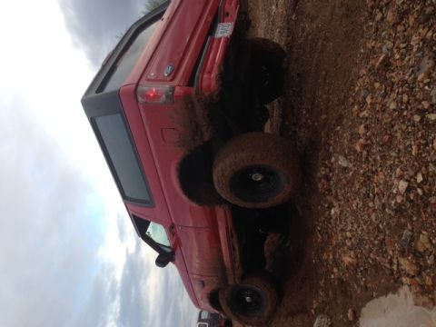 1996 Ford Bronco - This red 1996 Ford Bronco is heavily covered in mud, suggesting it has been off-roading.