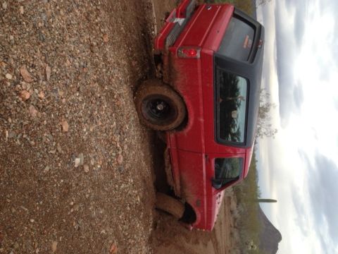 1996 Ford Bronco - A red 1996 Ford Bronco is stuck in the dirt off-road.