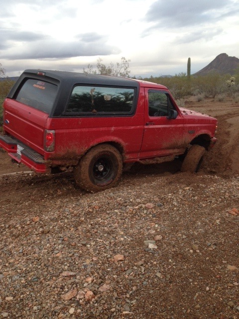 1996 Ford Bronco - This red 1996 Ford Bronco is stuck in the mud, with its front passenger side wheel deep in the mire.