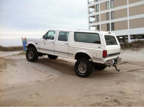 1995 Ford Bronco - This 1995 Ford Bronco extended cab sits on a sandy lot with a building in the background.