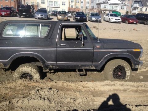 1979 Ford Bronco - This classic Ford Bronco is deeply embedded in the mud, with other vehicles visible in the background.