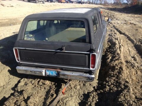 1979 Ford Bronco - A black 1978 Ford Bronco is stuck in the mud, viewed from the rear.
