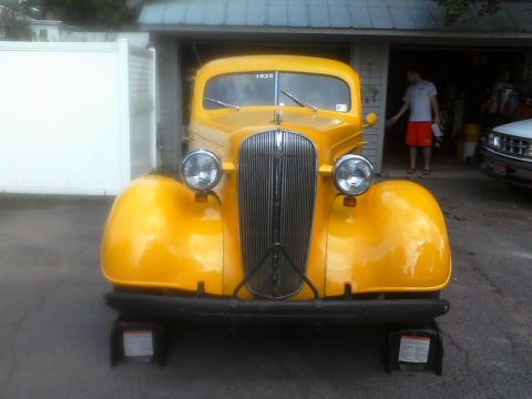 1935 Chevrolet New - A yellow 1935 Chevrolet truck is shown from the front, parked in front of a garage.