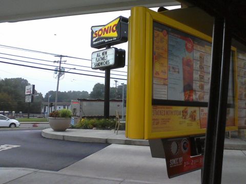1935 Chevrolet New - A Sonic Drive-In restaurant features its menu board and a sign advertising new flatmelt sandwiches.