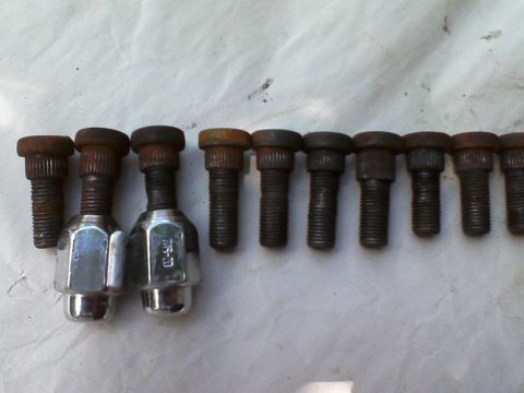 1935 Chevrolet New - A collection of lug nuts and bolts are laid out on a white surface.