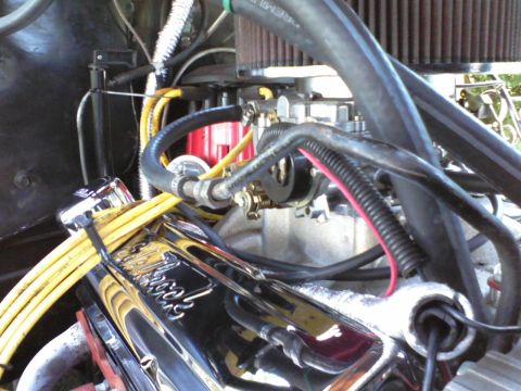 1935 Chevrolet New - A close-up view of an engine bay, highlighting a chrome valve cover and carburetor with associated hoses and wiring.