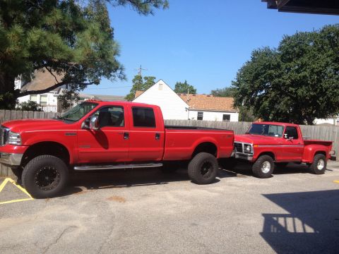 2007 Ford F-350 - A bright red 2007 Ford F-350 Super Duty pickup truck is shown parked next to a vintage red pickup truck on a sunny day.
