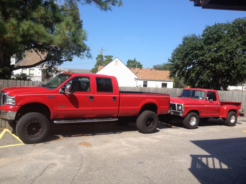 Side view of a red 2007 Ford F-350 Super Duty truck parked next to an older red pickup