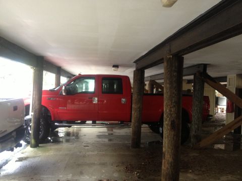 2007 Ford F-350 - A red crew cab pickup truck is parked under a covered area supported by wooden posts and metal beams.