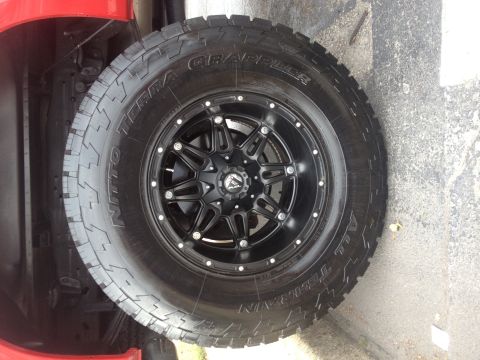 2007 Ford F-350 - Close-up of a red truck's wheel and tire assembly, black Fuel wheels and Nitto Terra Grappler tires.