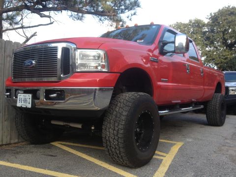 2007 Ford F-350 - This red 2007 Ford F-350 pickup truck is lifted with large off-road tires.