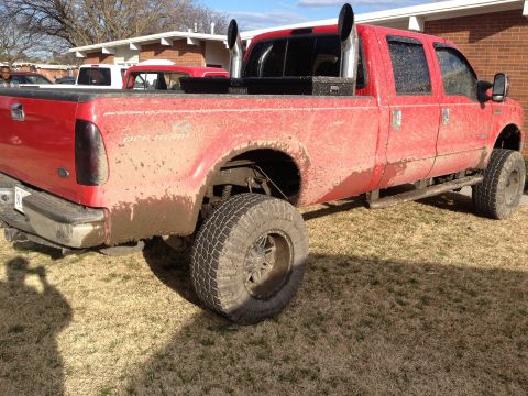 2007 Ford F-350 - Mud-covered 2007 Ford F-350 pickup truck with large exhaust stacks parked on grass.