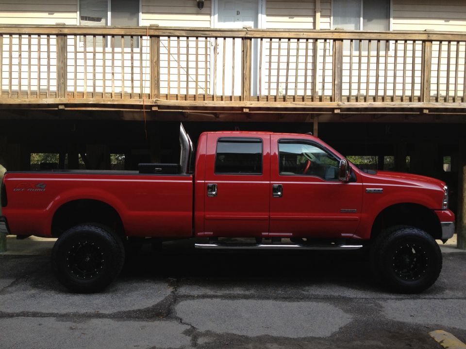 Side view of red 2007 Ford F-350 pickup truck with lifted suspension and large exhaust pipe