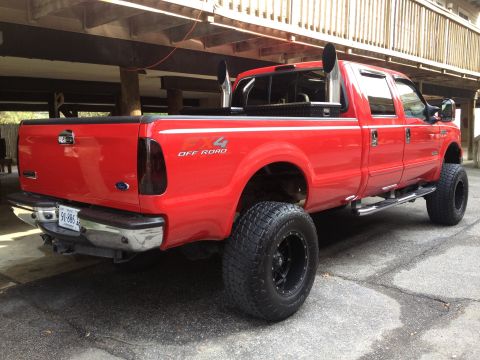 2007 Ford F-350 - Red 2007 Ford F-350 pickup truck with custom stacks and off-road tires.