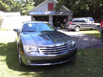 2004 Chrysler Crossfire - A gray Chrysler Crossfire is parked in front of a garage with another vehicle visible in the background.