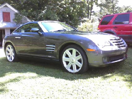 2004 Chrysler Crossfire - A gray Chrysler Crossfire is parked on a grassy lawn with a red SUV in the background.