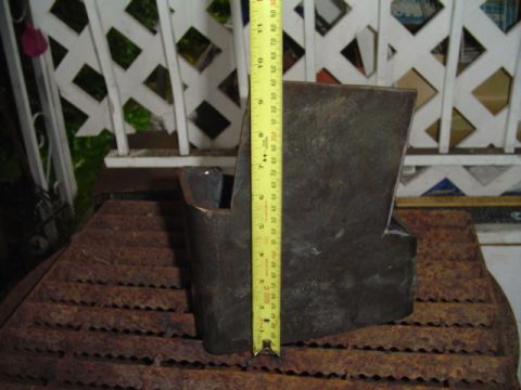 1993 Ford Bronco - A rusty fabricated steel bracket or frame section stood on end atop a corroded metal grate, with a yellow retractable tape measure held ver…