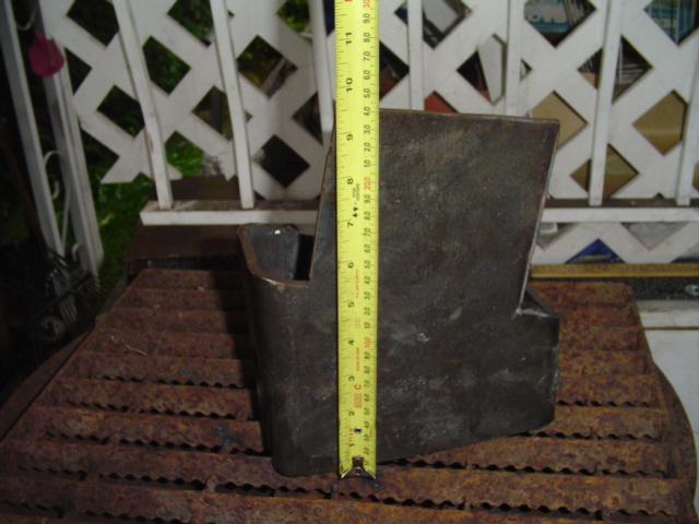 Rusty steel bracket measured with a yellow tape measure on a metal grate
