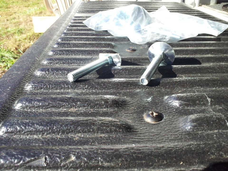 Truck bed liner with two bolts and a plastic bag of hardware