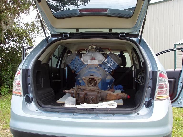 SUV's open trunk shows a large V8 engine and transmission loaded inside