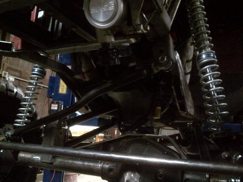 1985 Jeep CJ7 - Close-up view of the undercarriage of a heavily modified Jeep, showing suspension and drivetrain components.