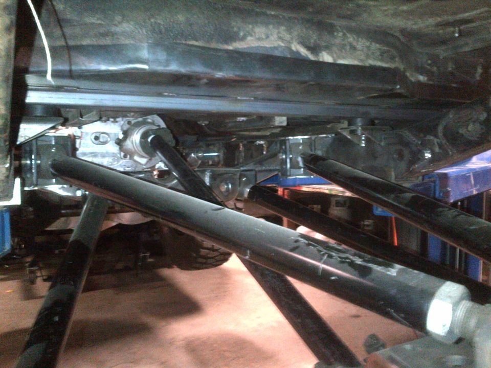 Underside of a vehicle on a lift, showing suspension and drivetrain components