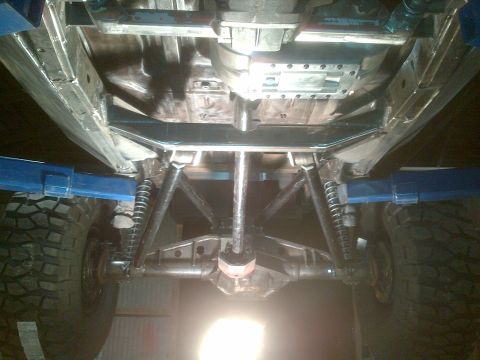 1985 Jeep CJ7 - The undercarriage of a vehicle is viewed from below while it is raised on a lift.