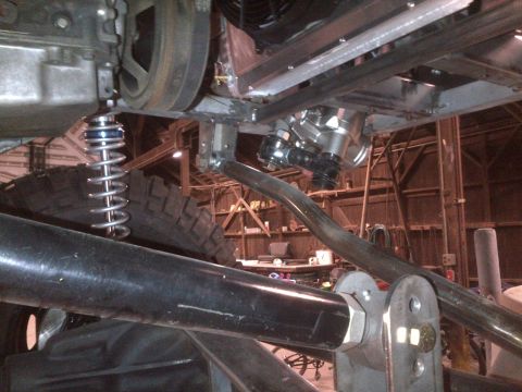 1985 Jeep CJ7 - Close-up of vehicle undercarriage components, including suspension and engine parts, with a Supermotors watermark visible.