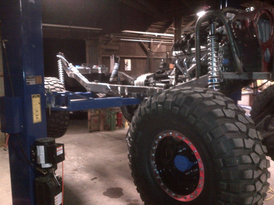 off-road vehicle frame on lift, large tires, roll cage visible