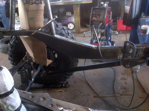 1985 Jeep CJ7 - A Jeep CJ frame is shown with suspension modifications and a welding machine in the background.