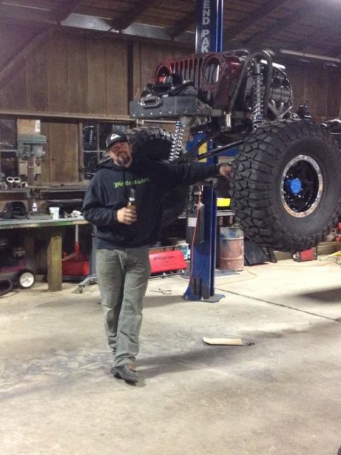 1985 Jeep CJ7 - Man stands by a 1985 Jeep CJ7 undergoing work on a lift in a garage.