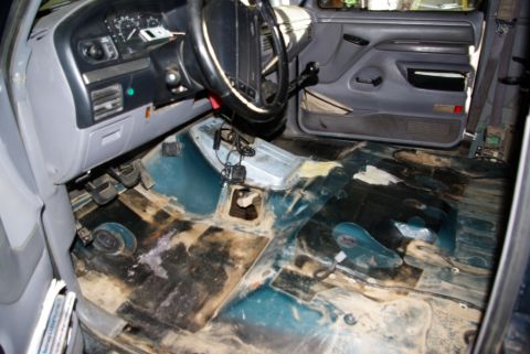 1995 Ford Bronco - The interior of a 1992 Ford Bronco shows a removed carpet and exposed floor pan, with the dashboard and steering wheel visible.