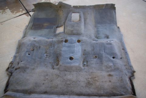 1995 Ford Bronco - Car floor carpet removed from vehicle, showing wear and mounting points.