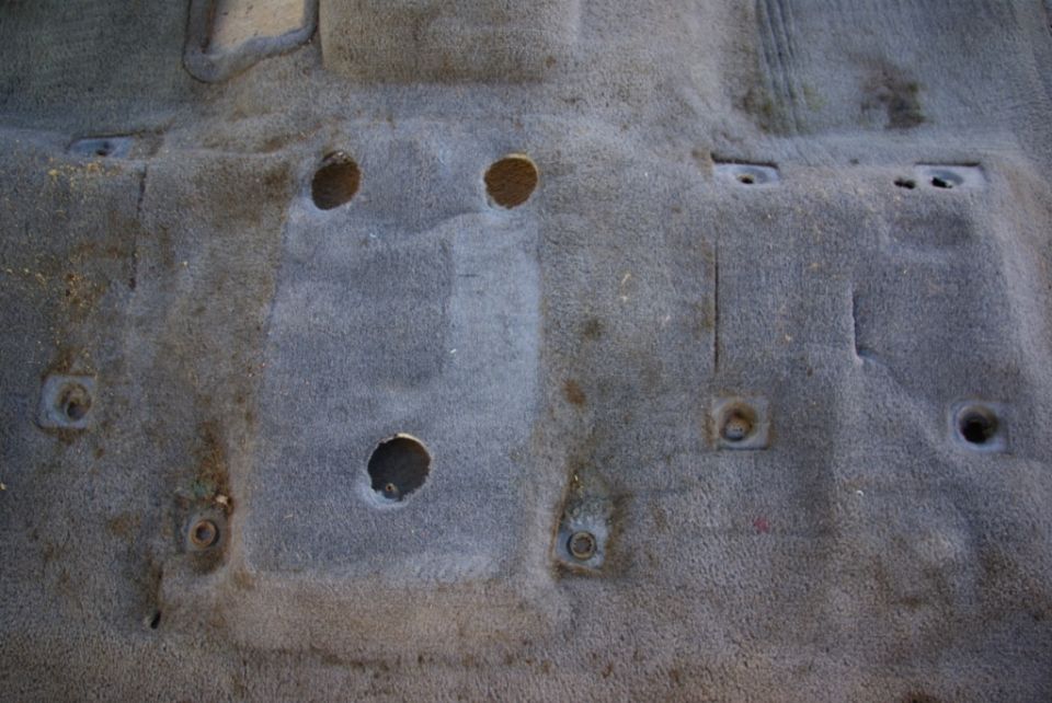 Carpeted floor with holes and mounting points visible