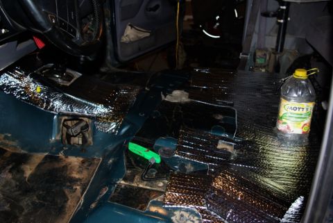 1995 Ford Bronco - The interior of a vehicle is being worked on, with sound dampening material applied to the floor.